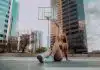 a woman sitting on the ground in front of a basketball hoop