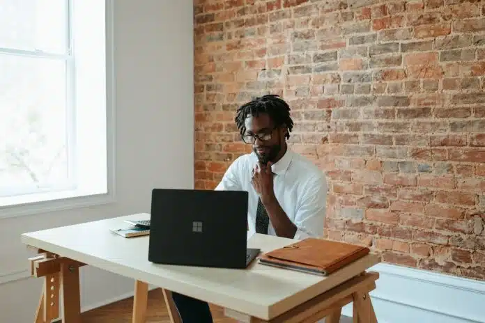 a man sitting at a table in front of a laptop