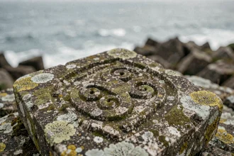Symbole triskel sculpté en relief sur une pierre de granit ancienne au bord de la côte atlantique